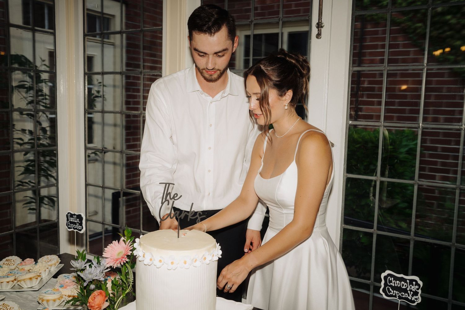 Couple cutting their wedding cake together at an elegant indoor reception.