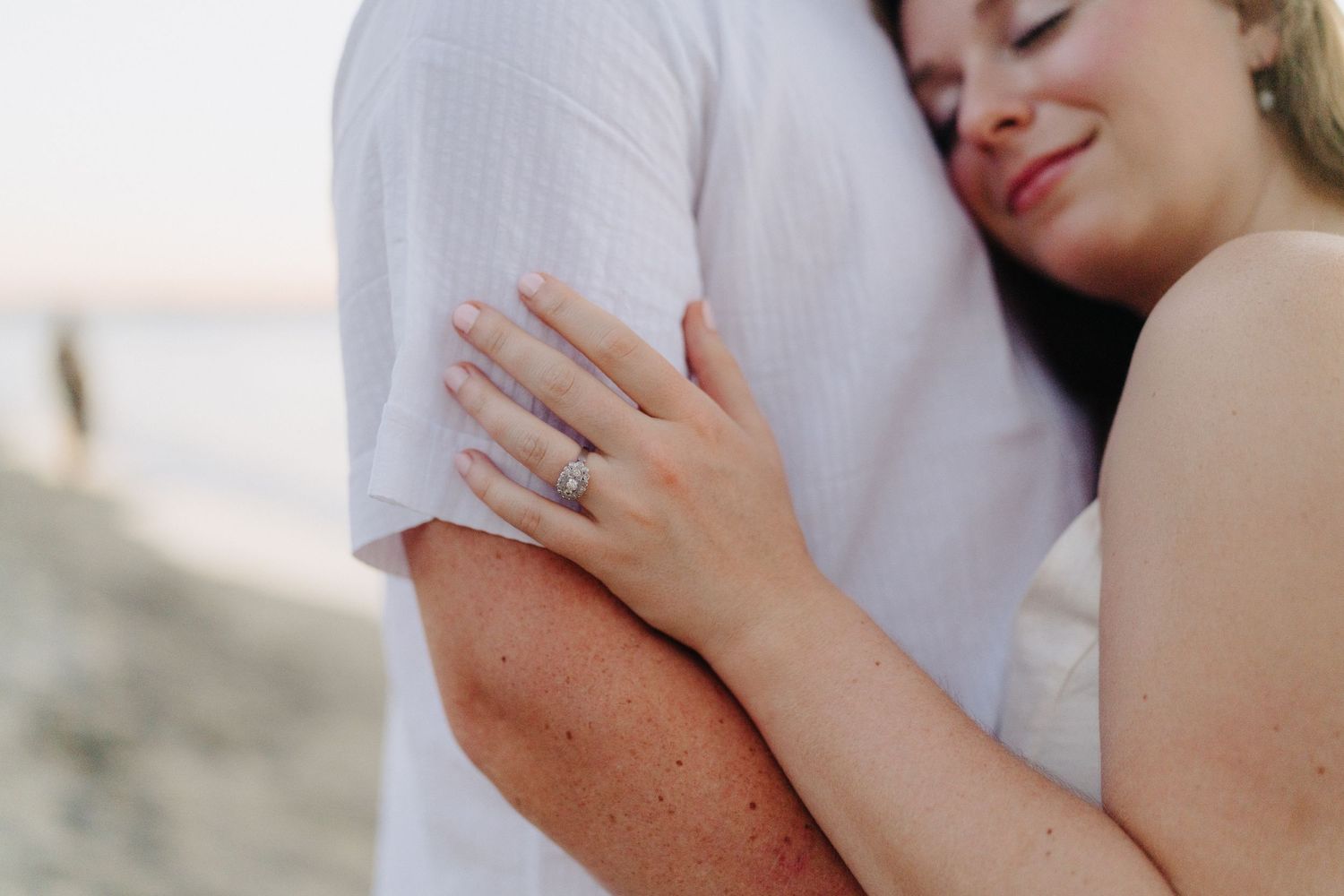 Close-up shot of a couple embracing tenderly on a sunny beach.