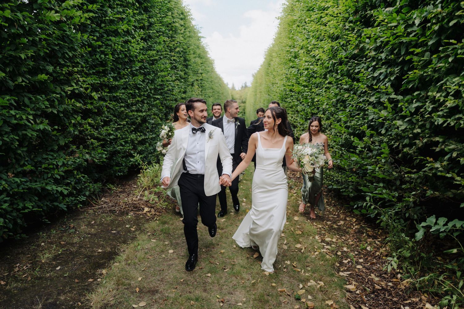 Tall manicured hedges line a garden path creating an elegant outdoor wedding venue.