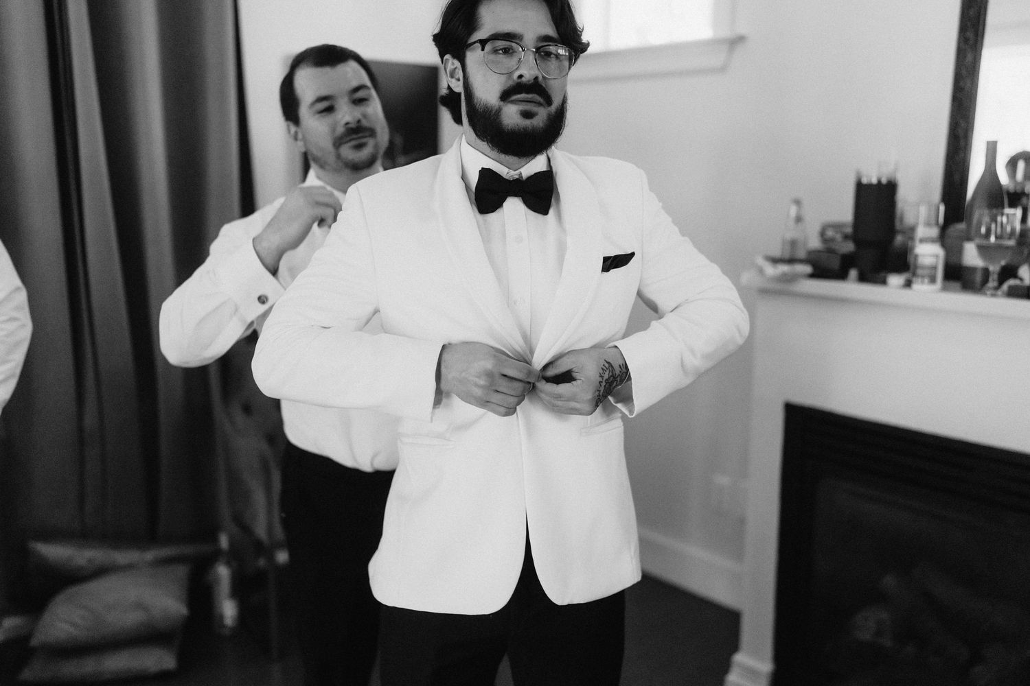 A group of people in white formal attire smile and pose together at an elegant event.