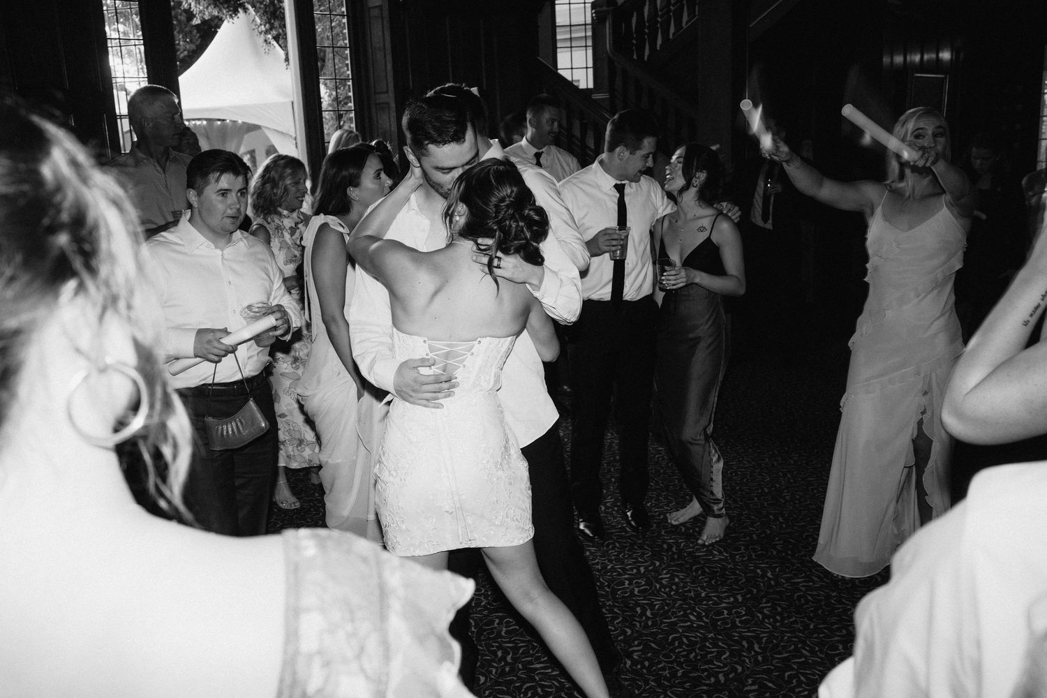 Black and white photo of wedding guests dancing and celebrating on a packed dance floor.
