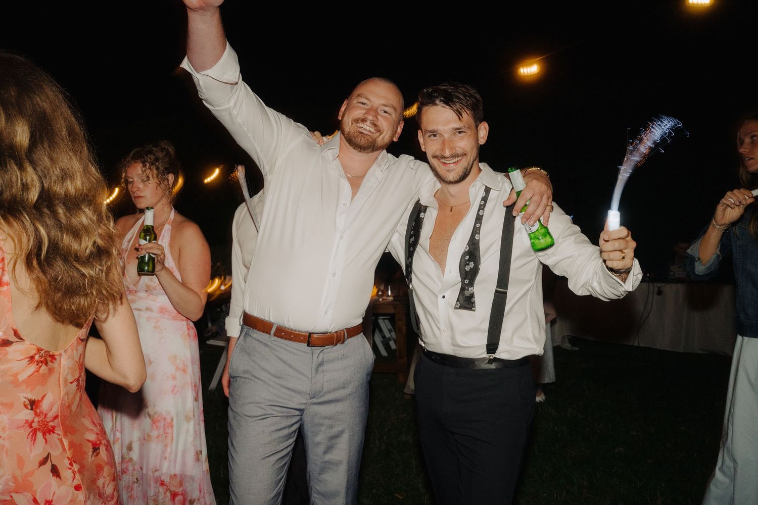 Joyful celebration at nighttime wedding reception with guests dancing.