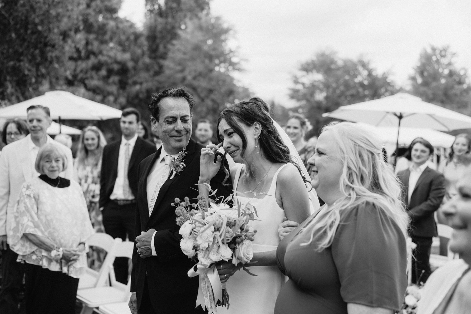 Black and white photo of wedding guests mingling at an outdoor reception.