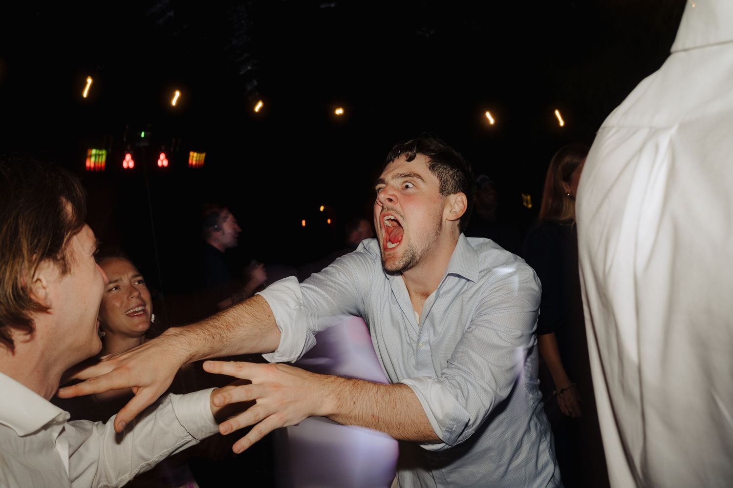 Energetic dance floor moments captured during nighttime wedding reception.