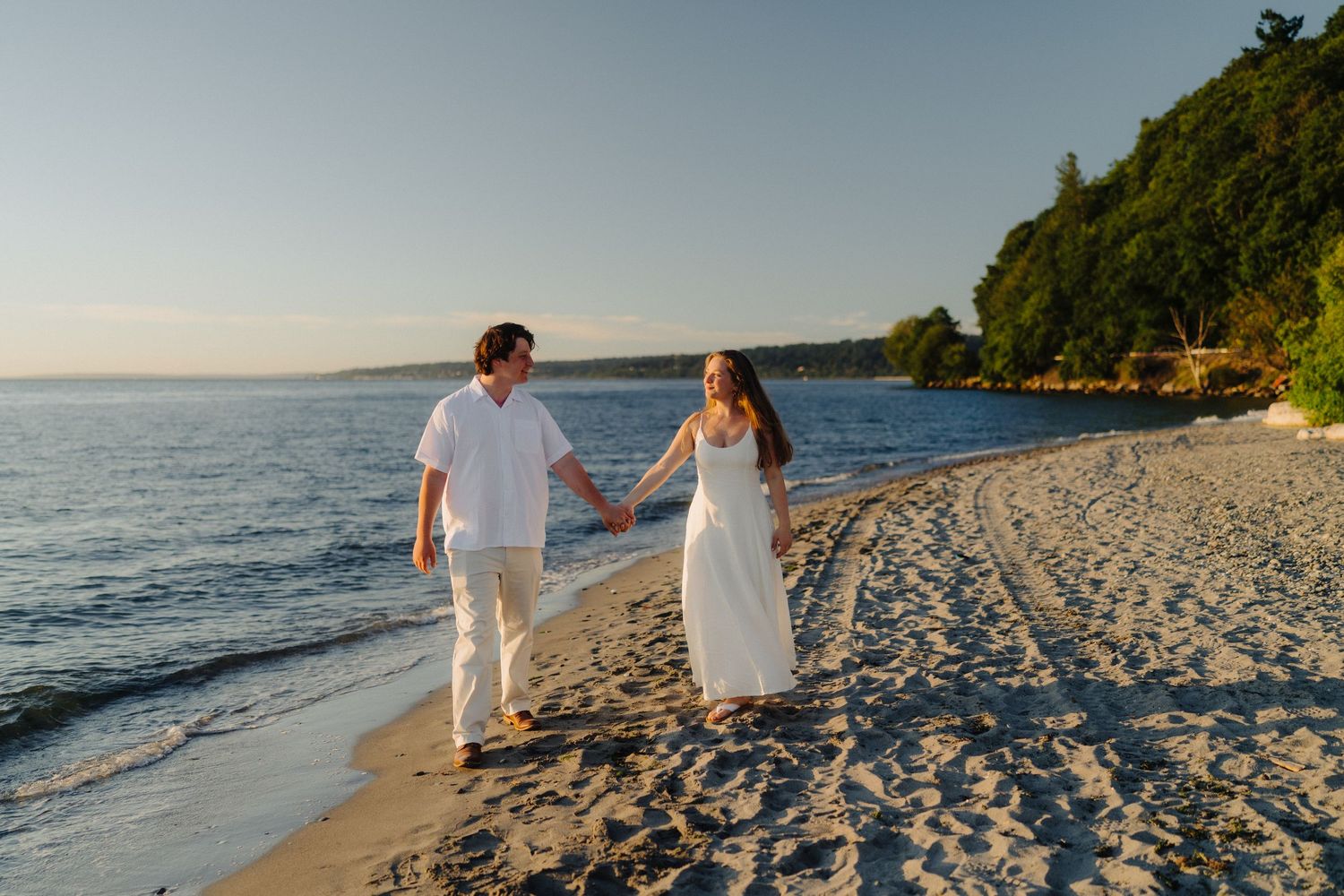 Couple enjoying a romantic moment on a scenic beach with cliffs and water views.