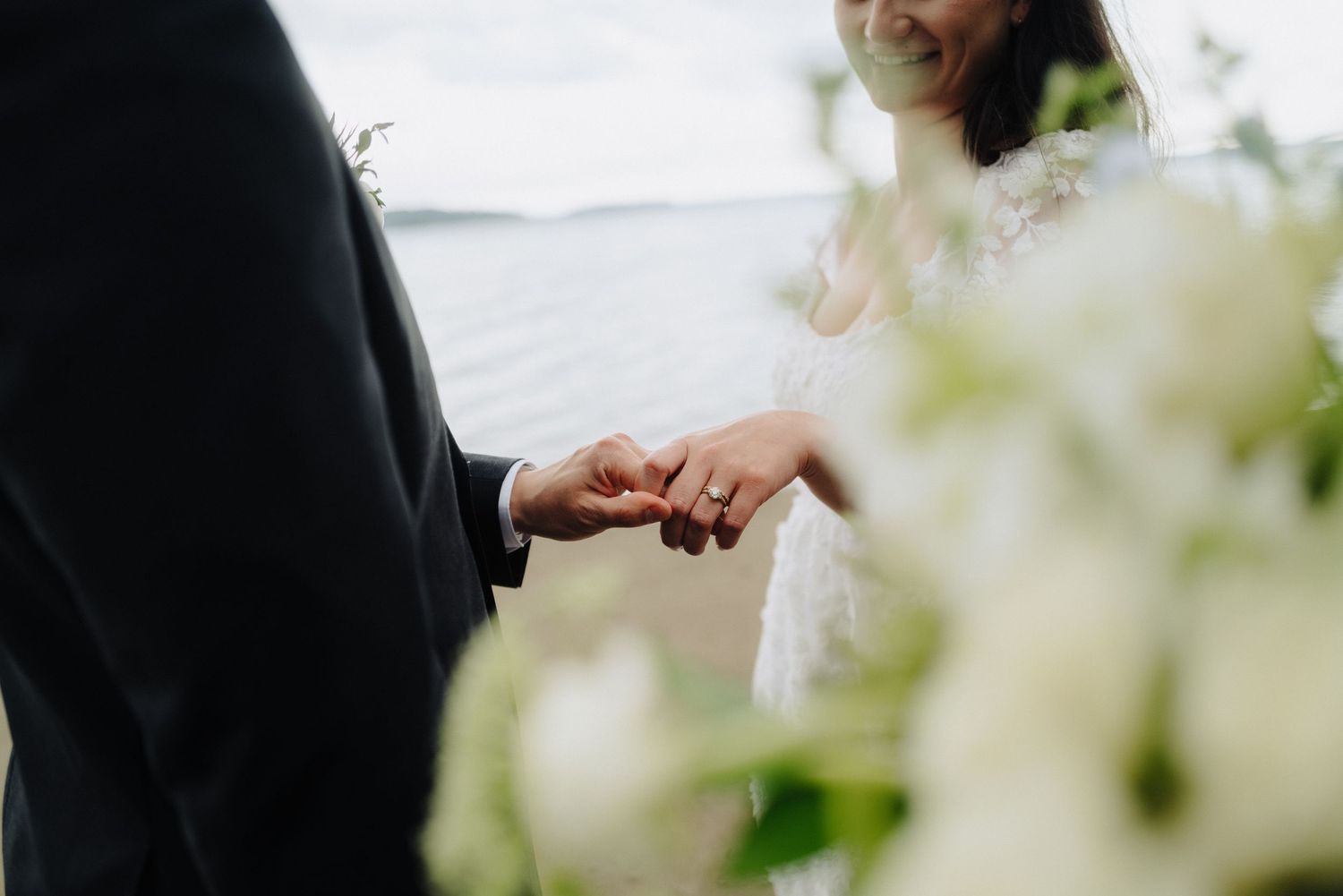 A close-up view of hands exchanging wedding rings during an outdoor ceremony.