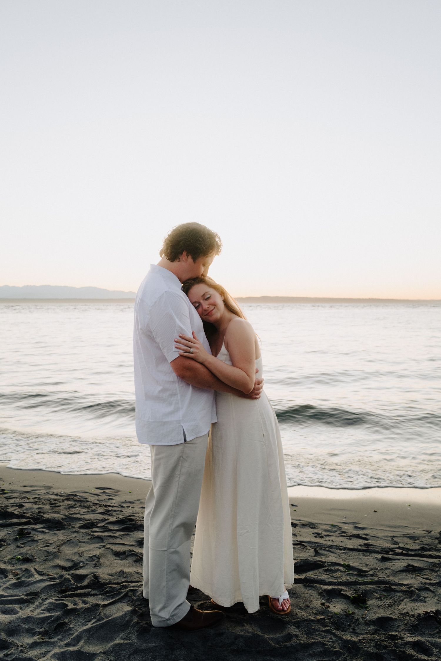 Tender embrace on sandy beach during golden hour sunset.
