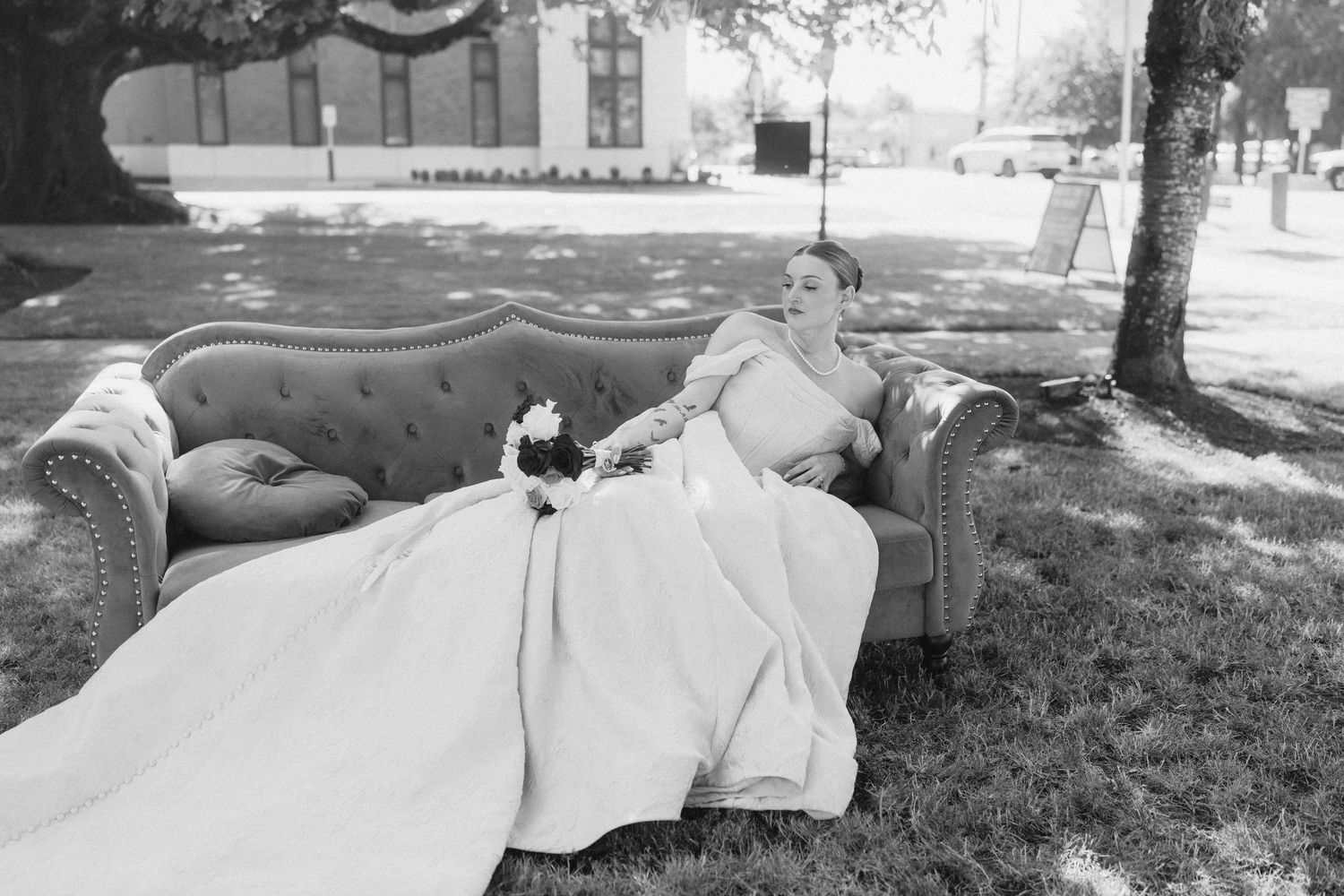 Black and white photo of wedding dress train spread across grassy lawn.