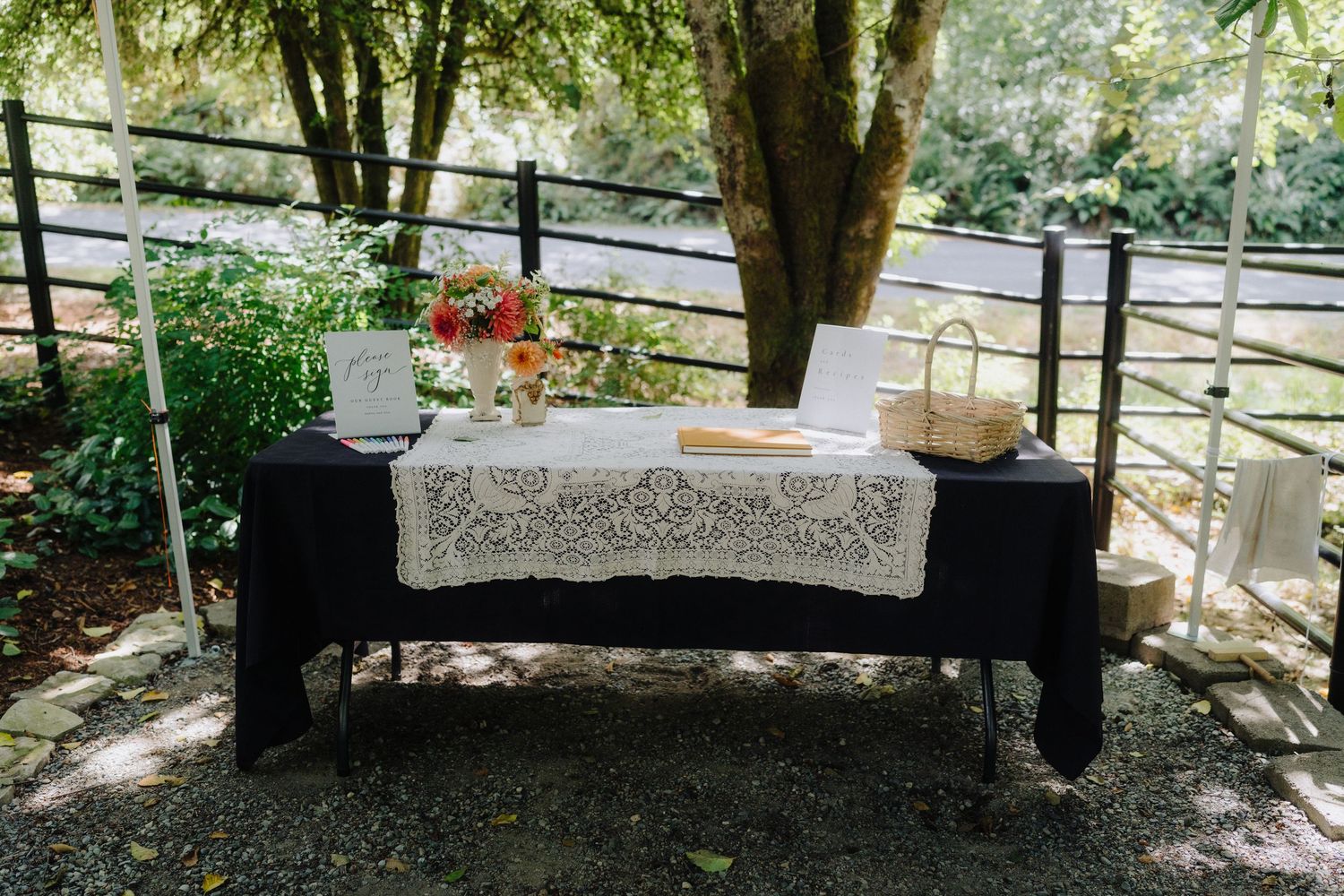 Elegant buffet table with lace tablecloth and floral arrangements set in a shaded outdoor garden setting.