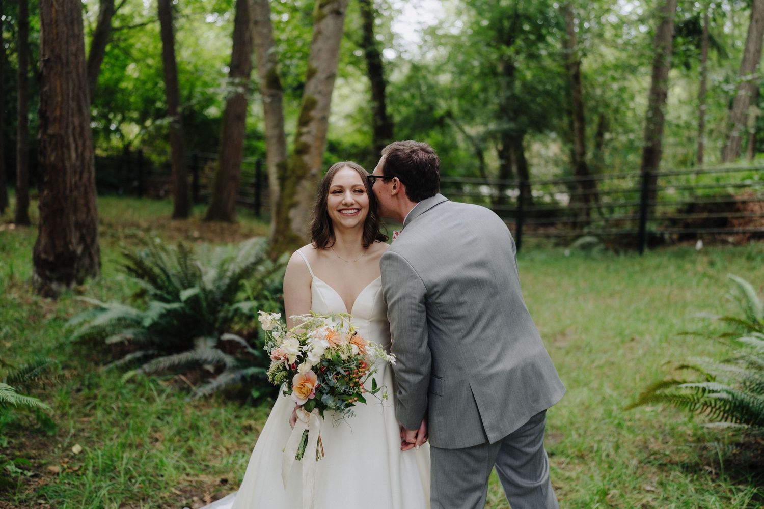Couple shares intimate moments during outdoor wedding photos in a lush forest setting.