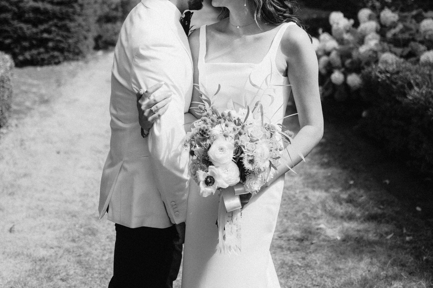 Wedding party poses for formal portraits in an outdoor garden setting.