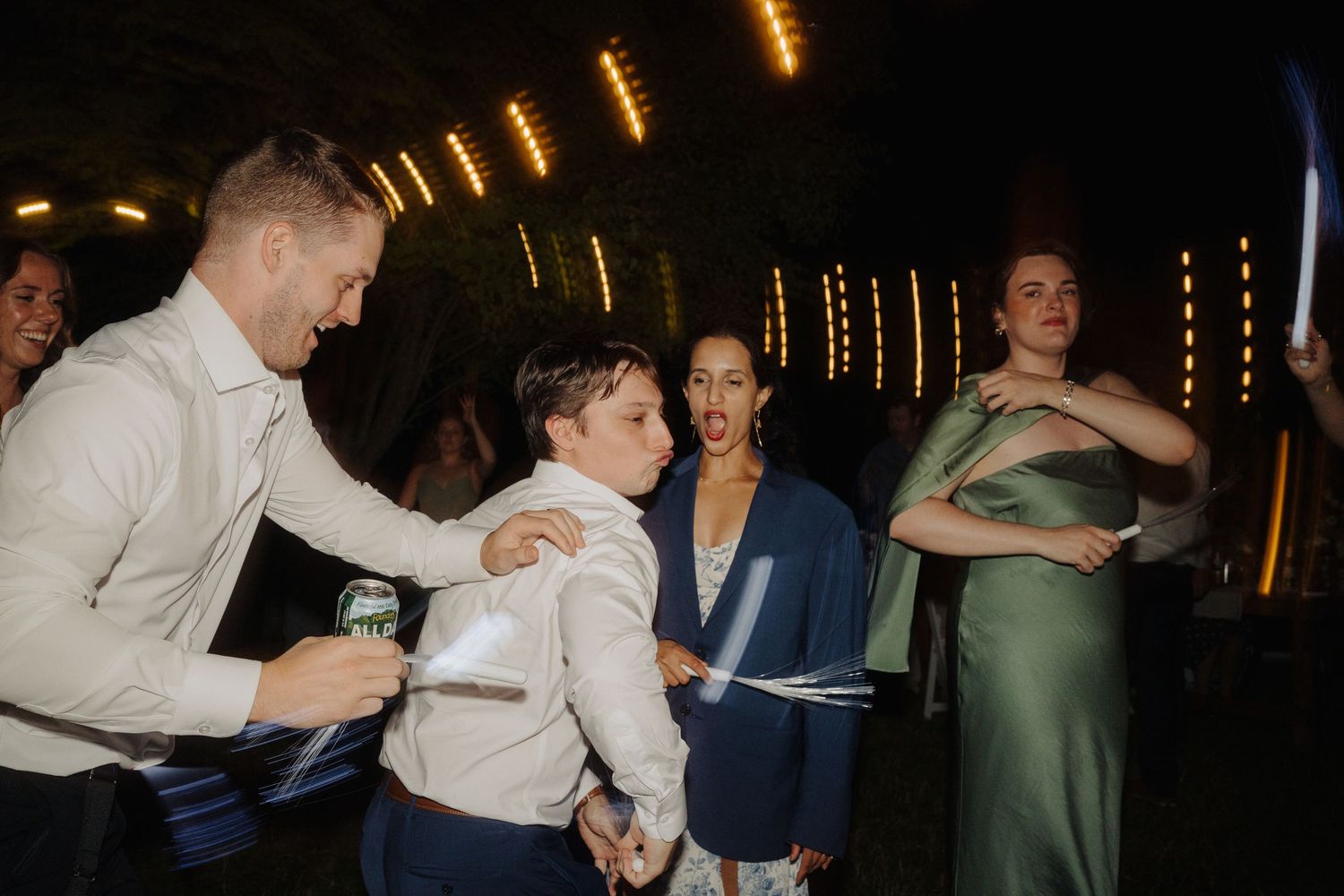 Guests enjoying a lively dance party at an evening wedding reception with warm lighting.