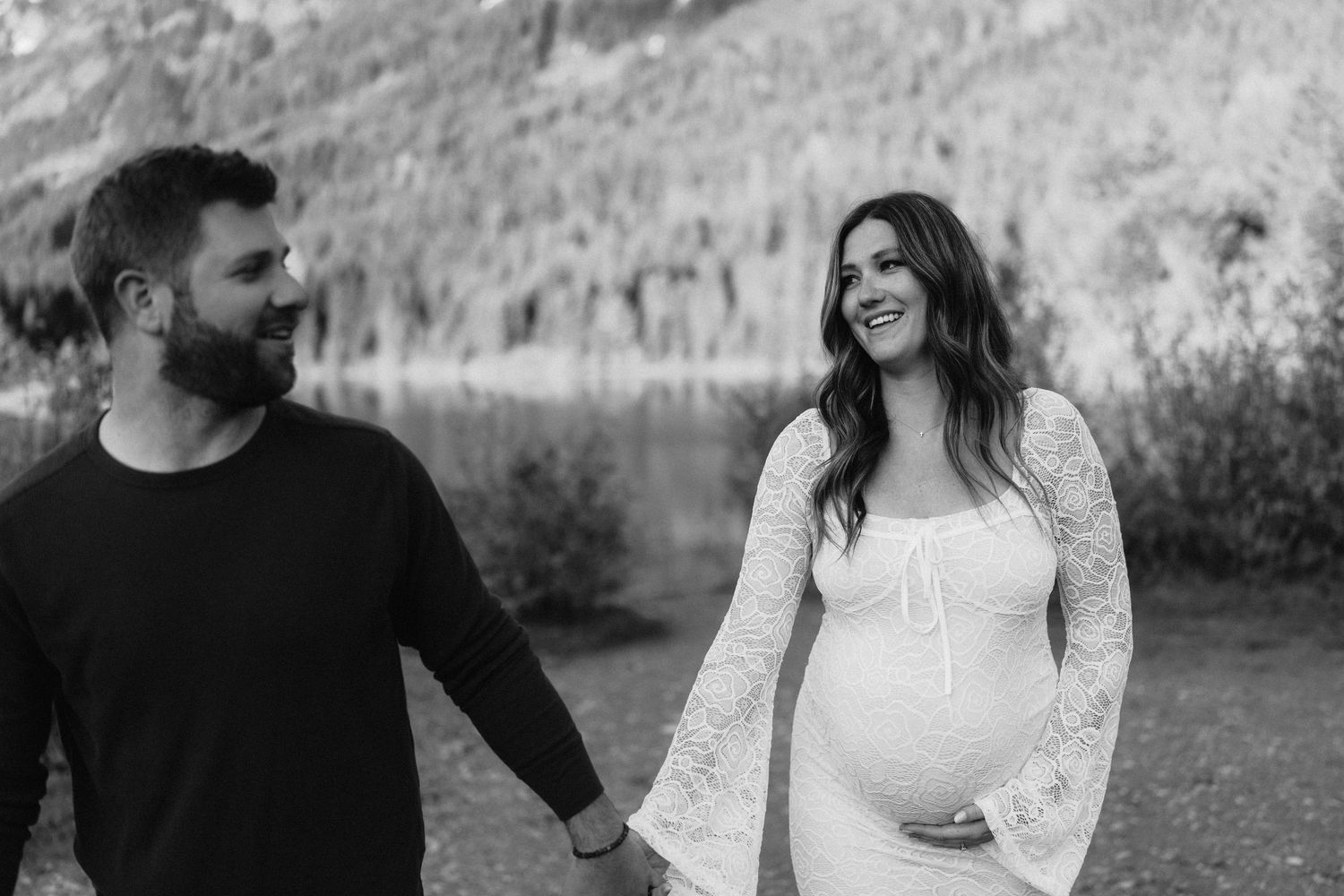 Black and white portrait of couple sharing tender moment by scenic mountain landscape.