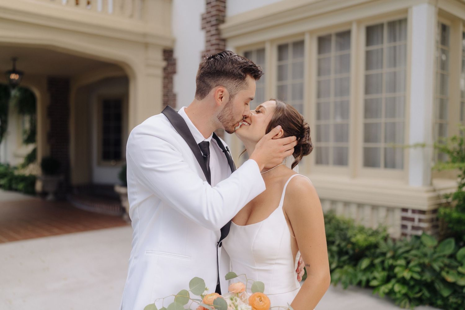 Elegant couple sharing intimate moment against classic white architectural backdrop.
