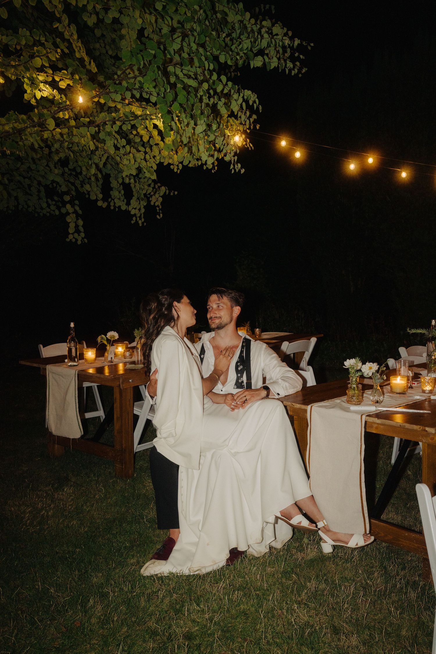 Evening outdoor reception with string lights and white-covered chairs.
