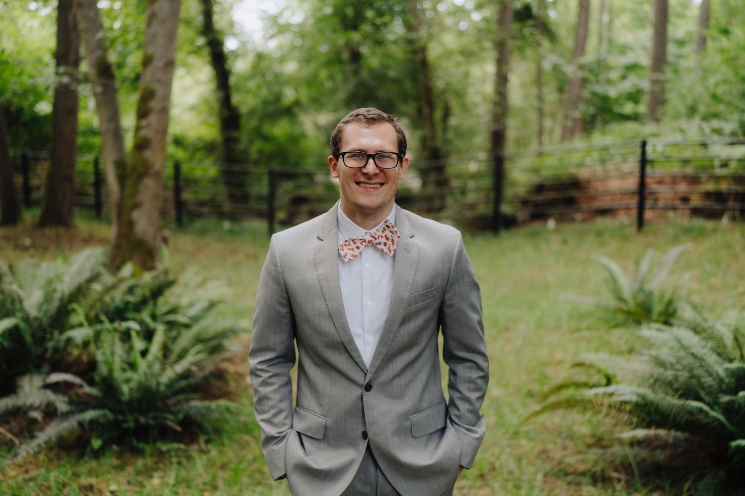 Wedding portraits captured in serene woodland setting with grey suit and white dress.