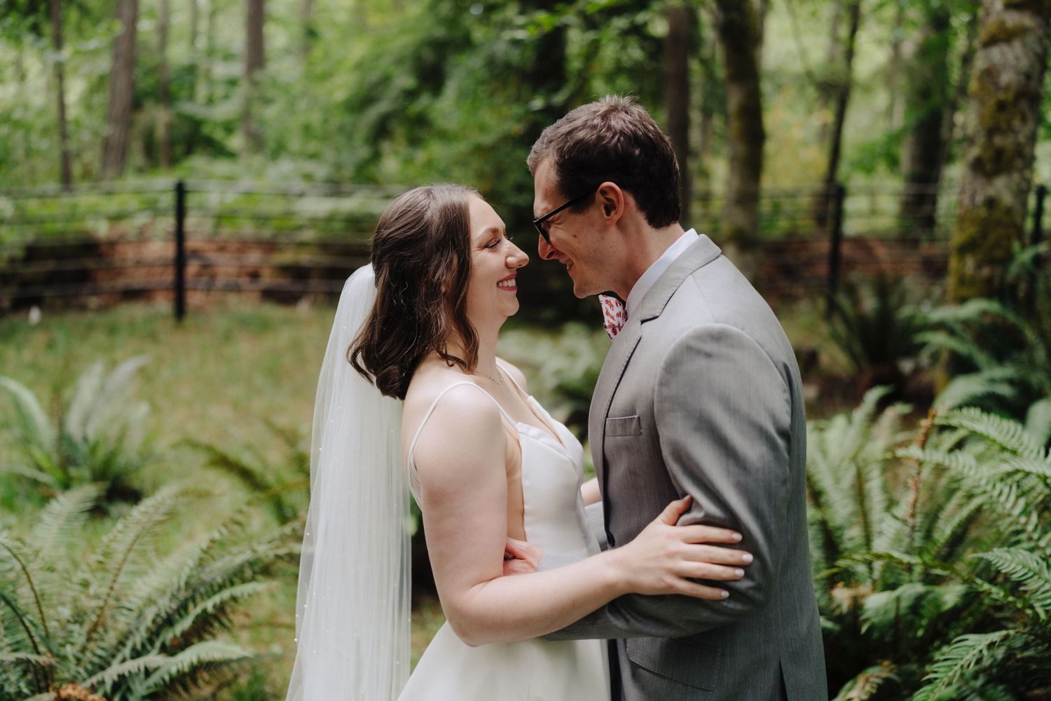 Romantic wedding portraits captured in a lush forest setting with ferns.