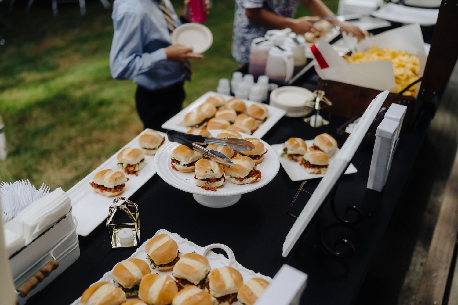 Wedding reception buffet table with plates of fresh hamburgers.