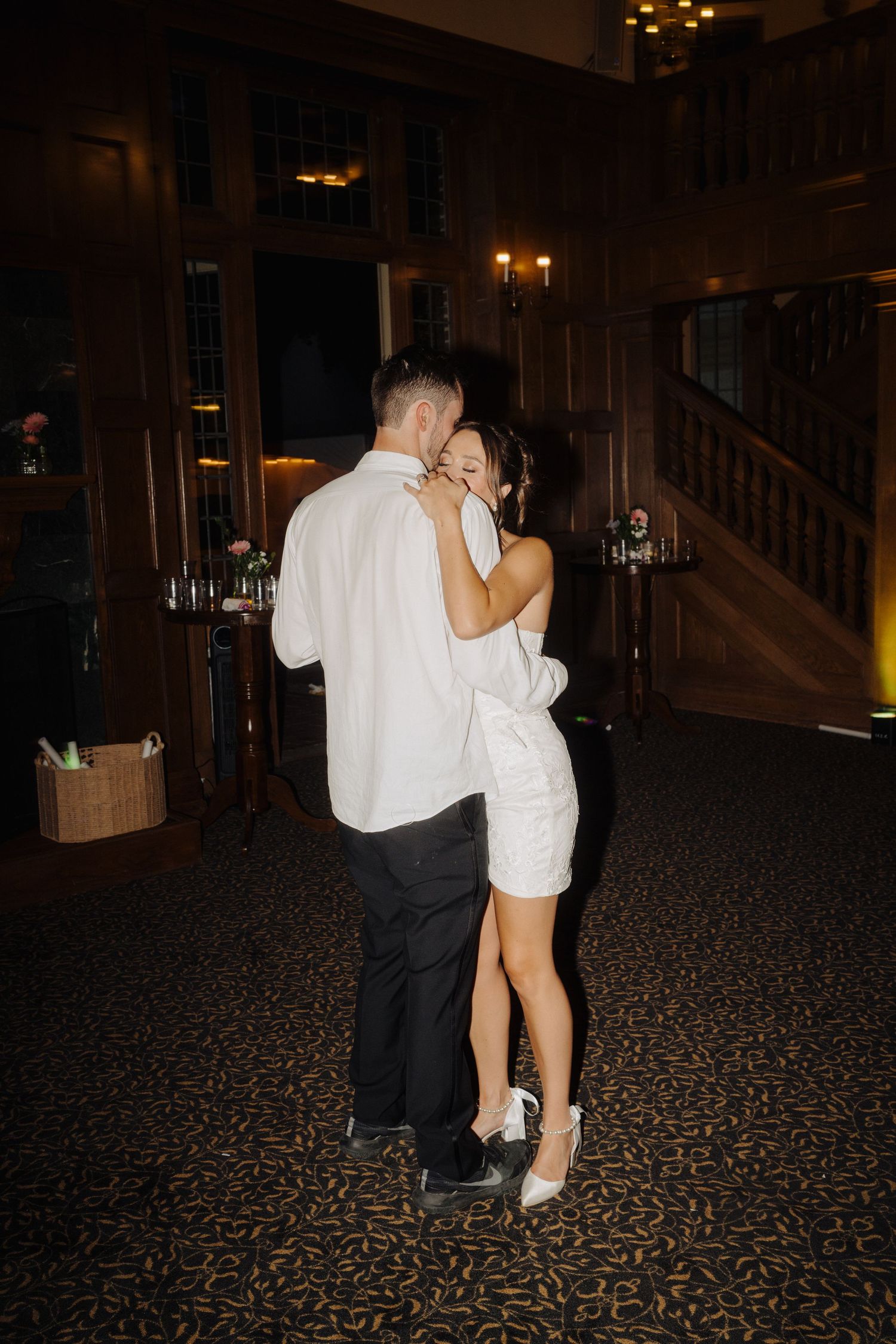 Romantic slow dance moment on patterned carpet during evening wedding reception.