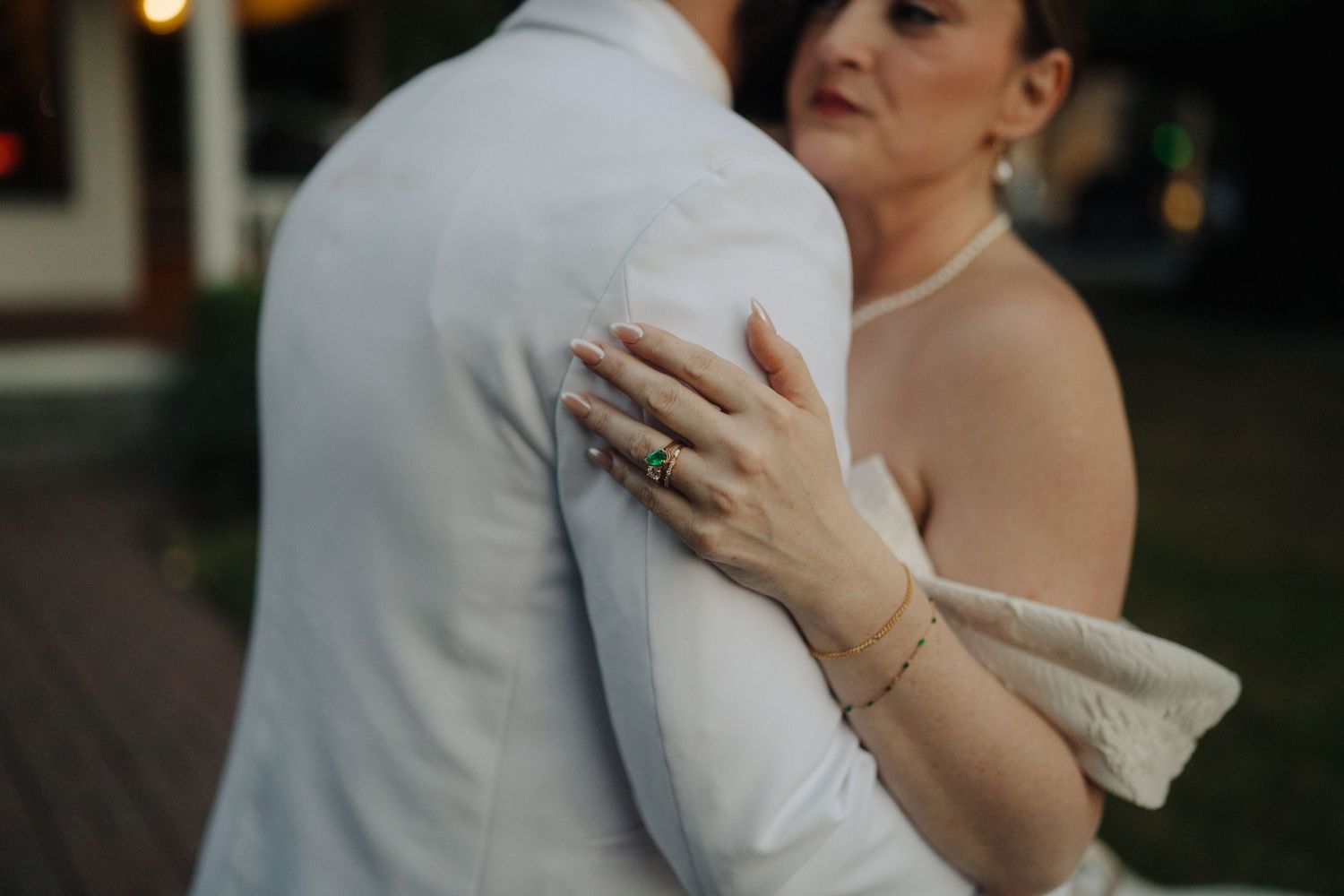 Close-up of a couple embracing during a wedding dance, showing the bride's elegant ring and bracelet.