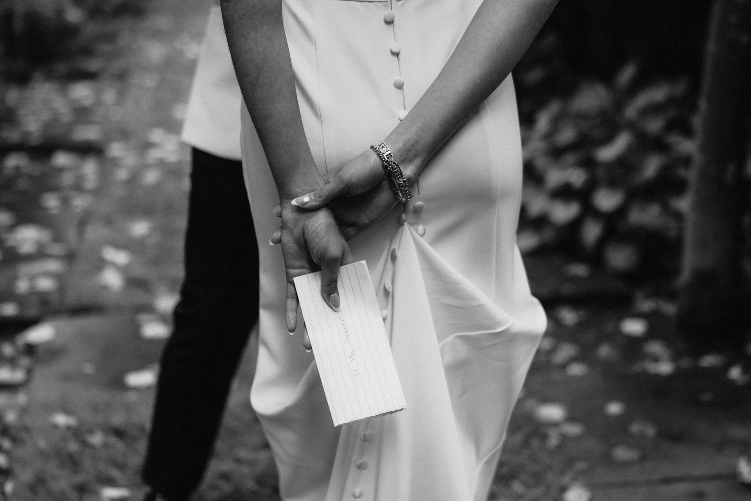 Black and white wedding photo showing couple embracing during outdoor confetti celebration.