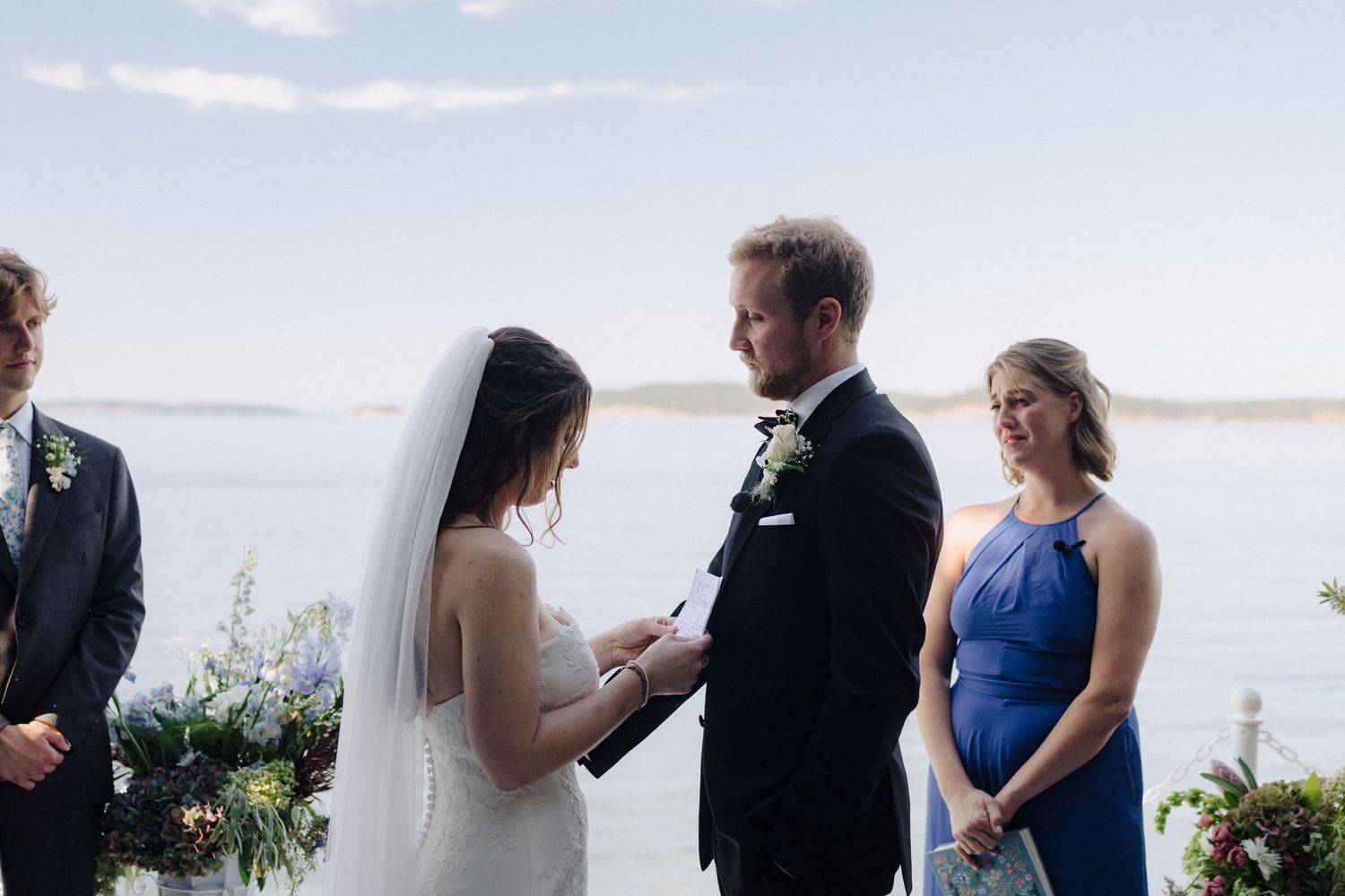 Wedding ceremony in progress with water and sky views in the background.