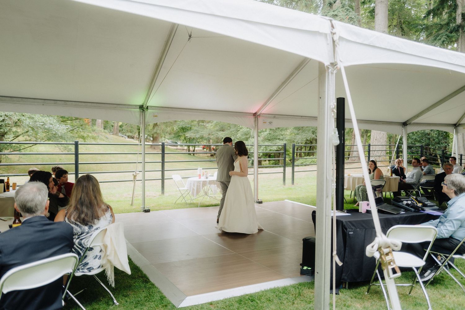 White wedding tent set up outdoors with tables and chairs for reception.