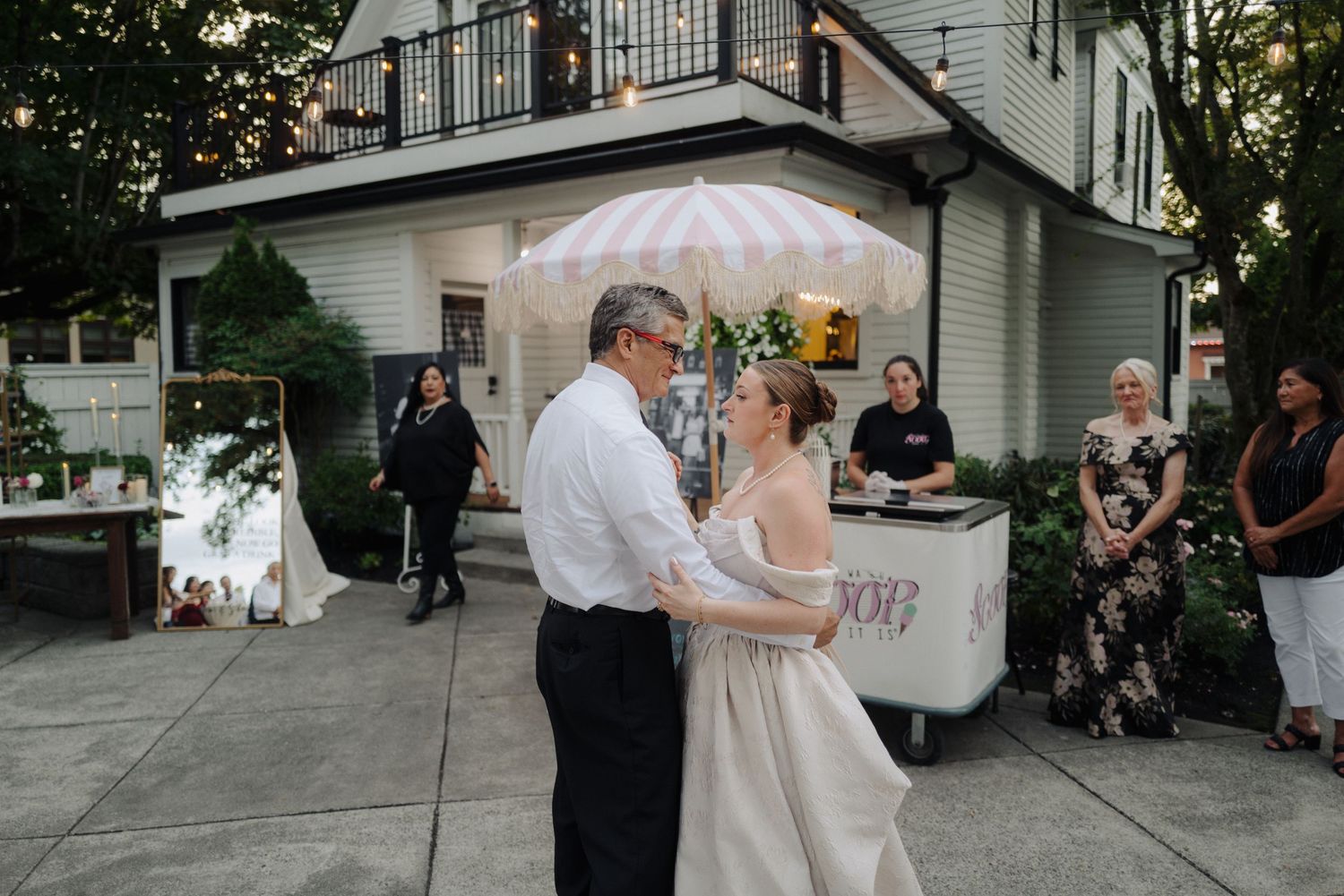 Wedding celebration with guests dancing on outdoor terrace during evening reception.