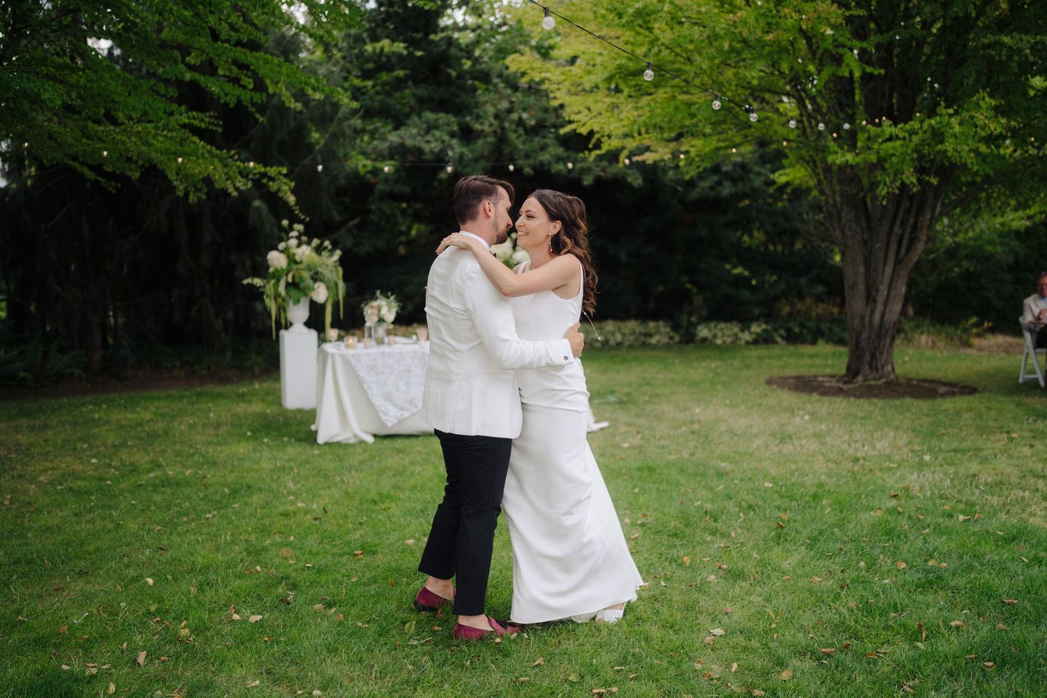 A garden wedding reception features white decor and natural landscaping.