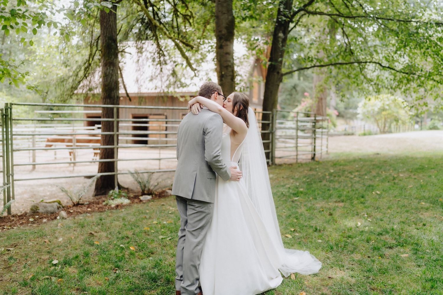 A romantic outdoor wedding scene with a couple embracing among lush green trees.