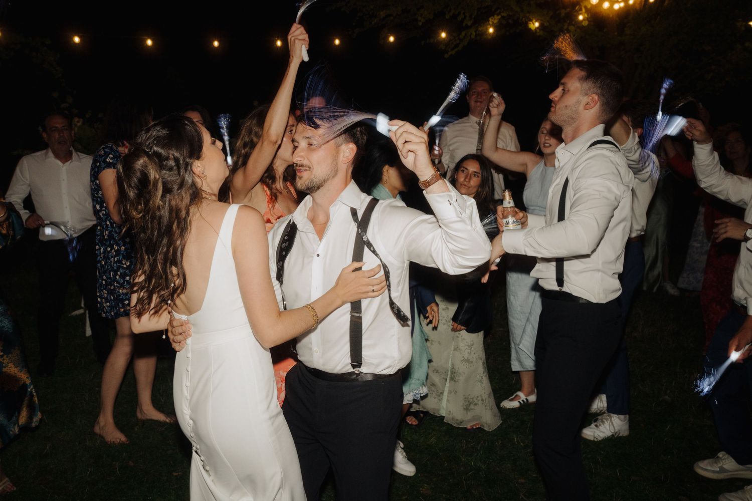 Wedding reception dance party at night with string lights creating a festive atmosphere.