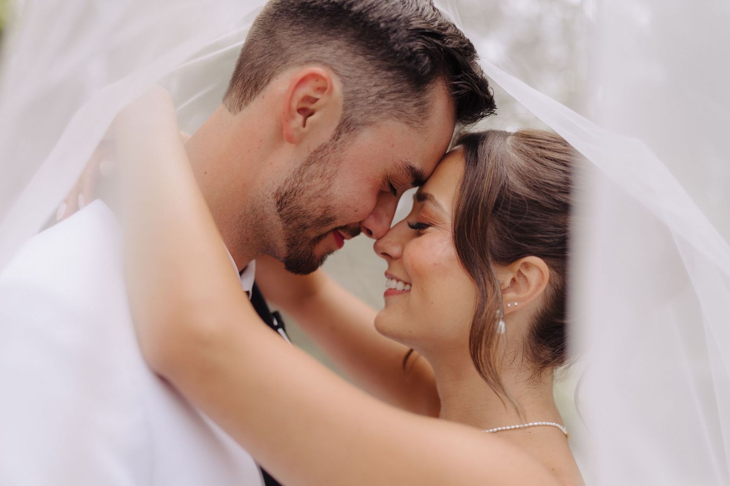 Romantic wedding moments captured in soft light with flowing white veil.