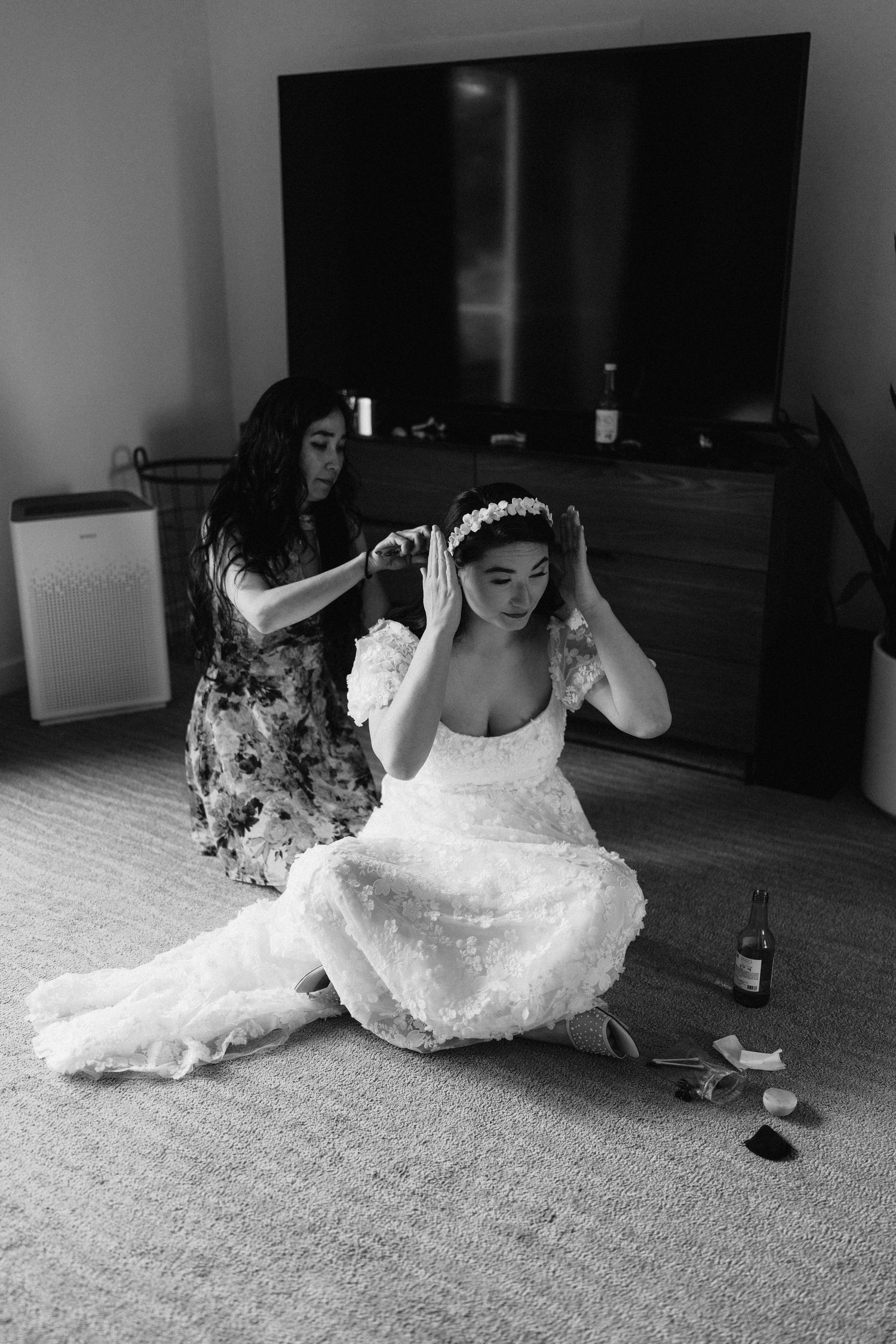 A white lace wedding dress flows across a carpeted floor in an artistic black and white photo series.