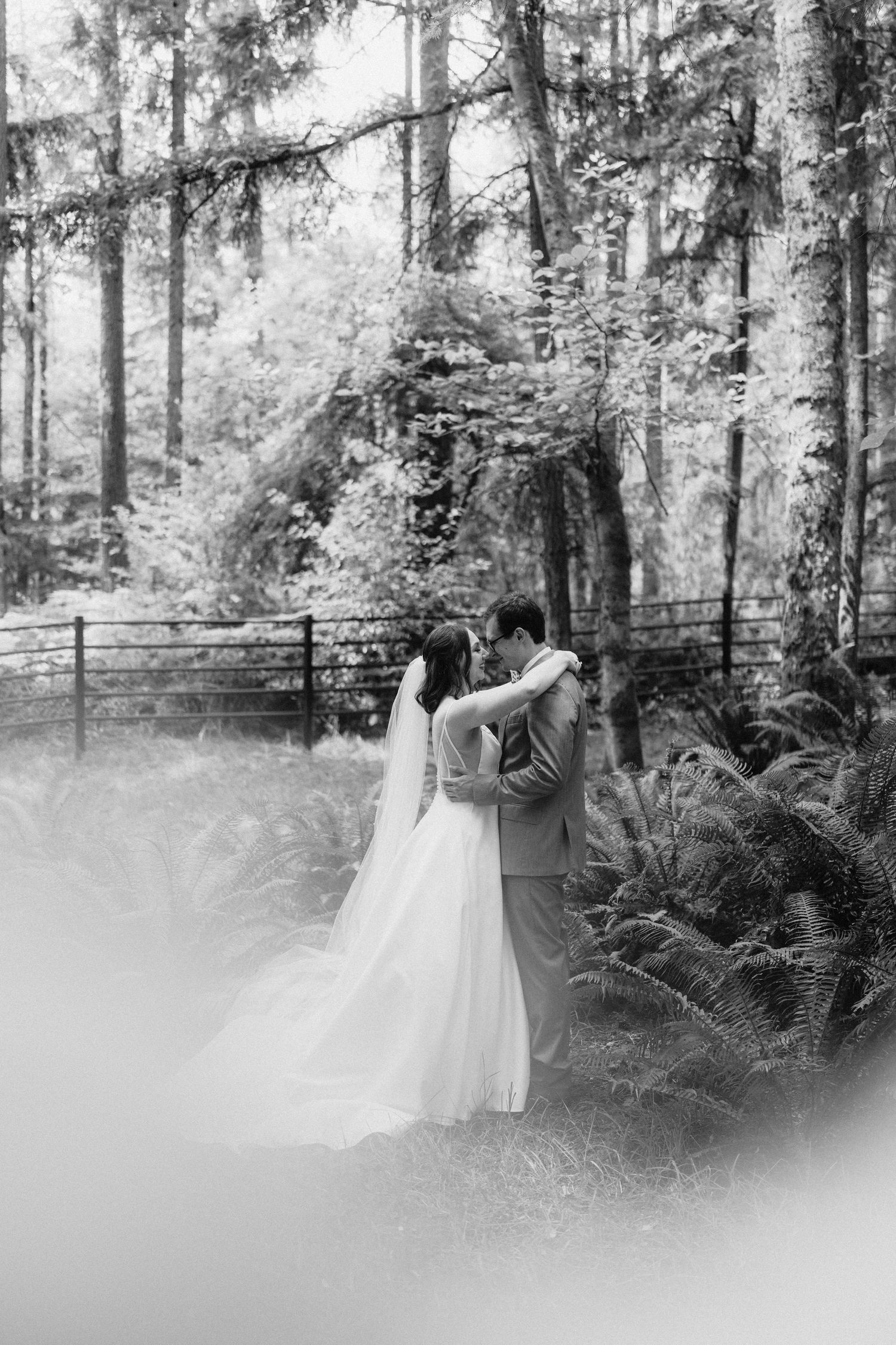 Black and white wedding photos capture romantic moments between newlyweds in a serene forest setting.