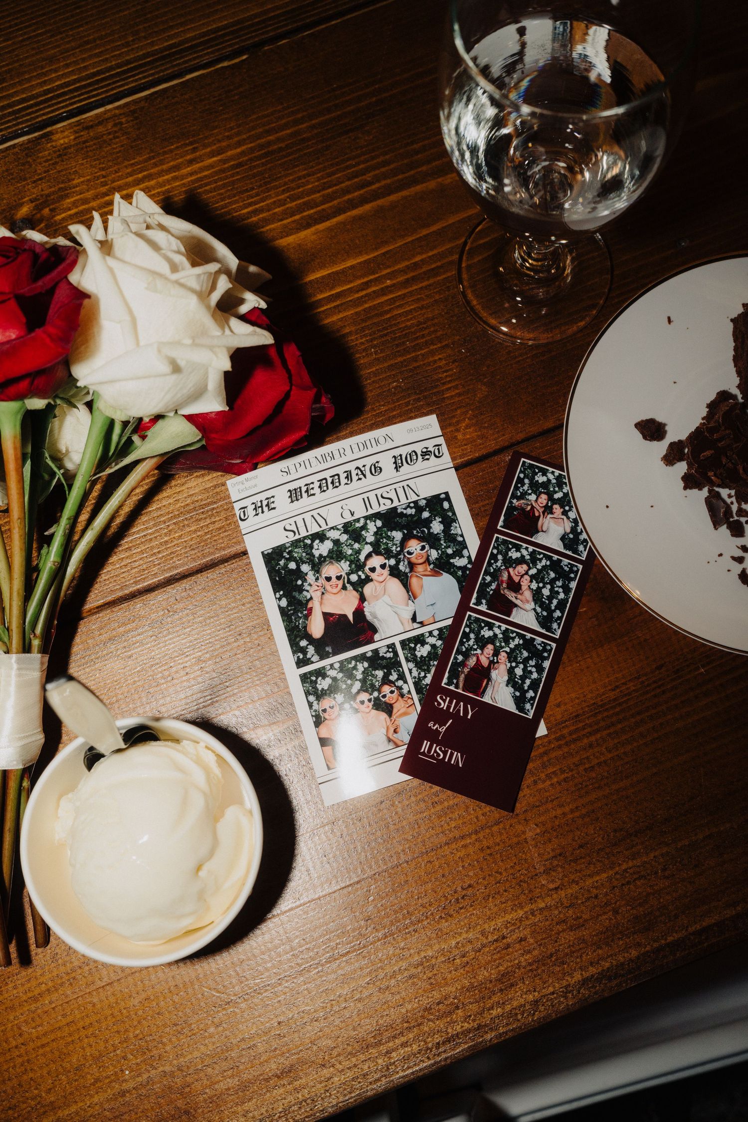 Wedding reception details with photo strips and white roses on dark wooden table.