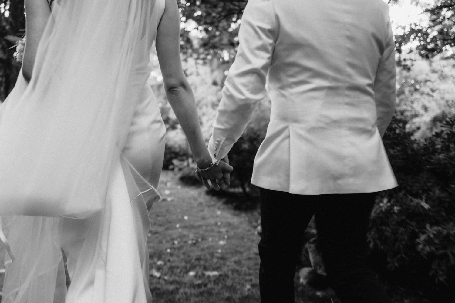 Black and white photo of wedding guests mingling at an outdoor reception.