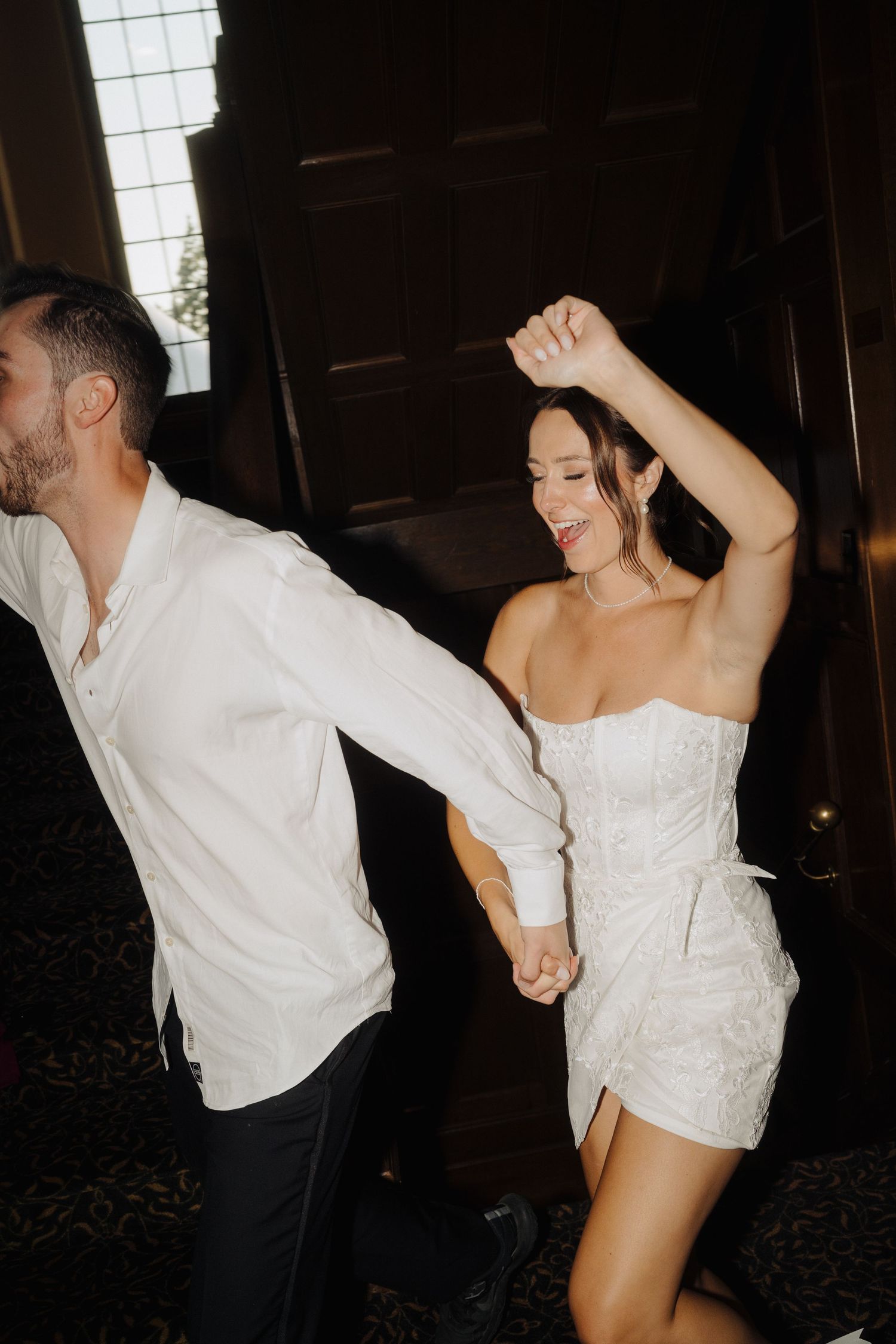 A couple dances joyfully in formal attire during their wedding celebration.