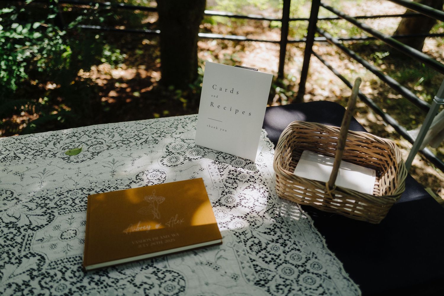 Wedding guest book and decorative items arranged on lace tablecloth in natural lighting.