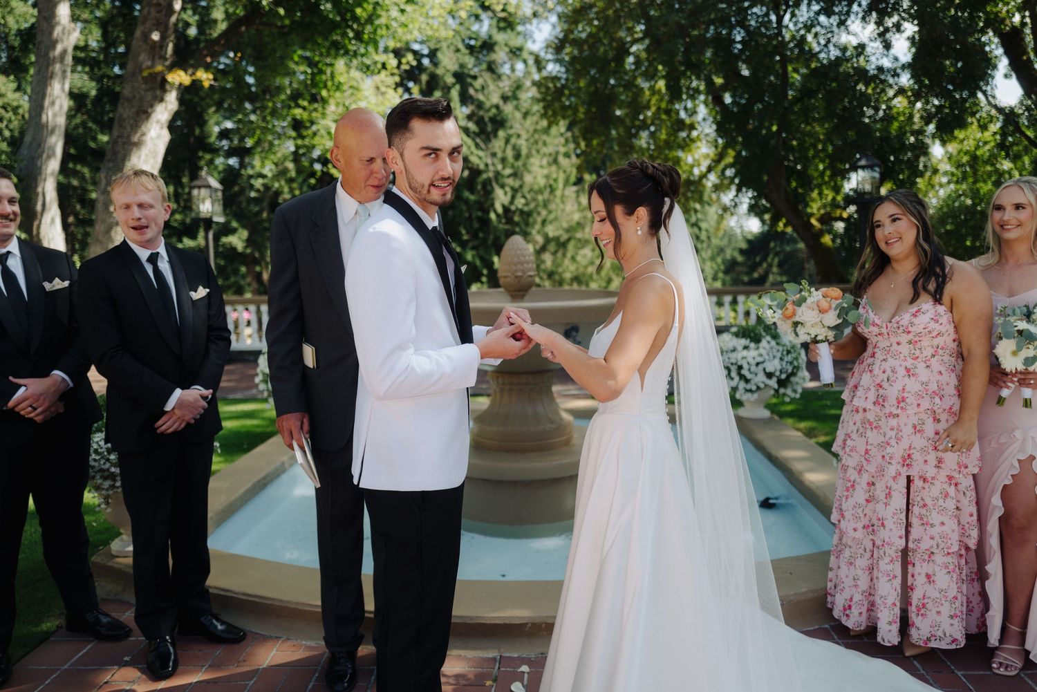 Outdoor wedding ceremony in progress with floral decorations and guests watching.