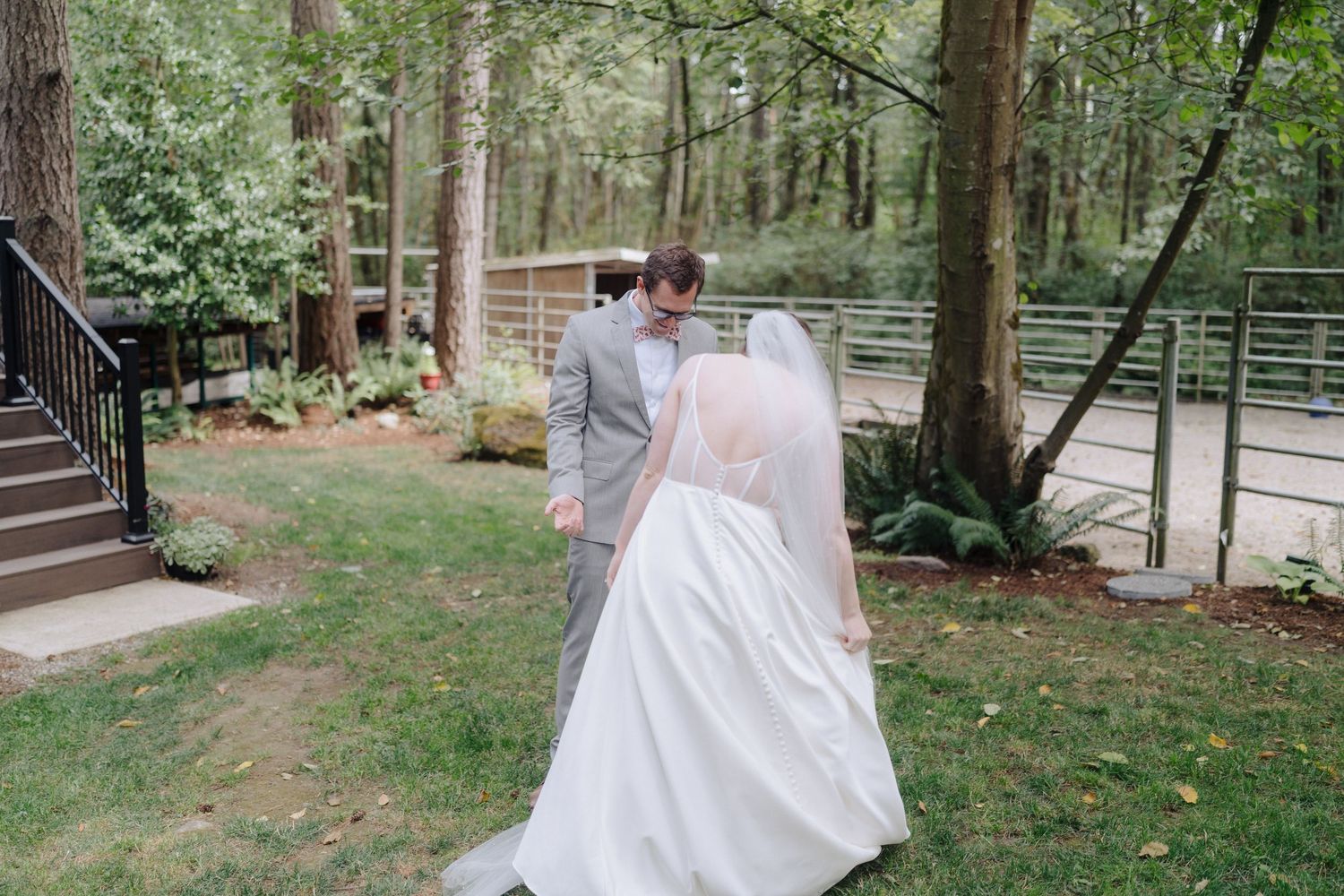 A couple shares an intimate moment in a wooded outdoor setting during their wedding celebration.