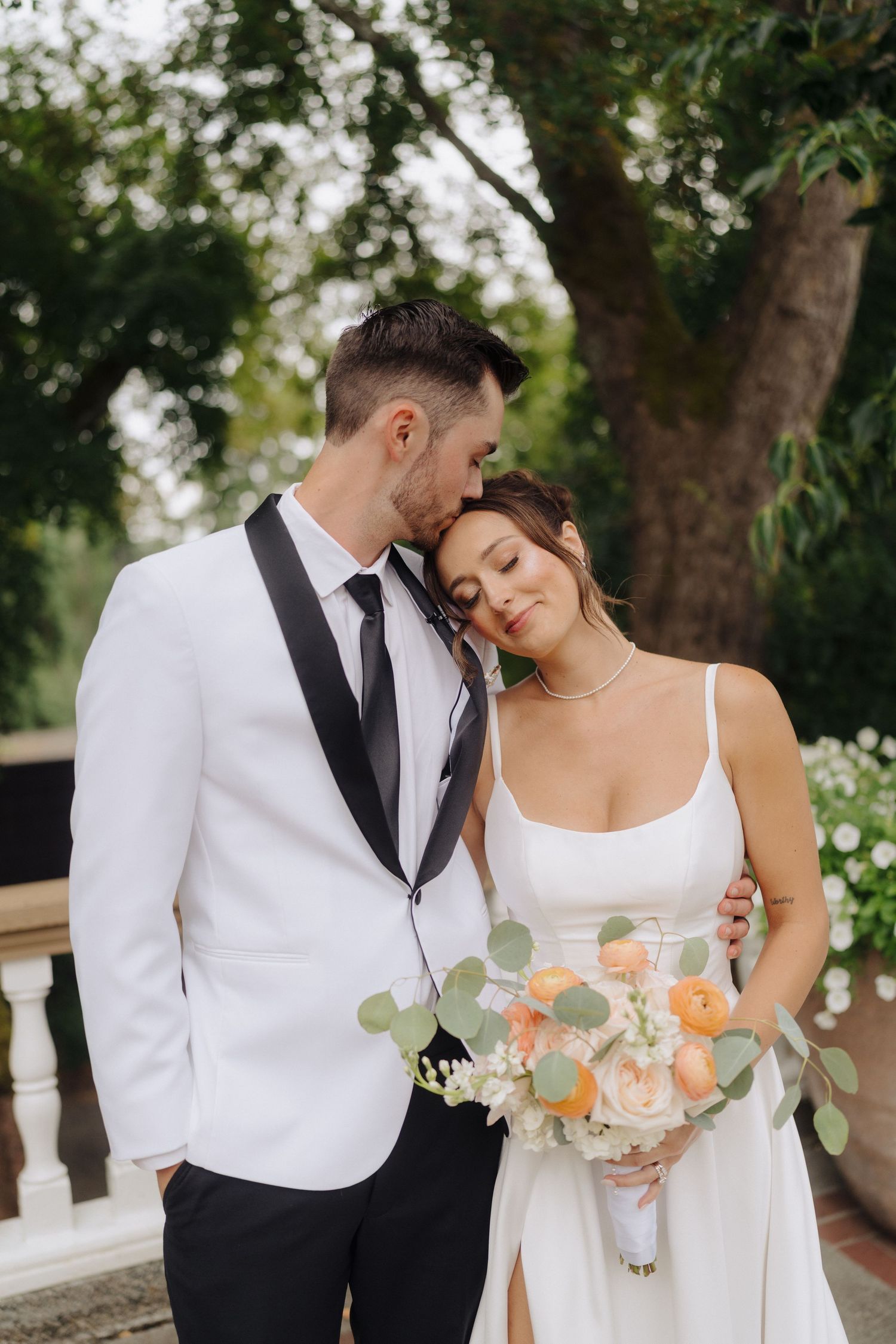 A romantic wedding portrait outdoors with soft peach roses and eucalyptus bouquet.