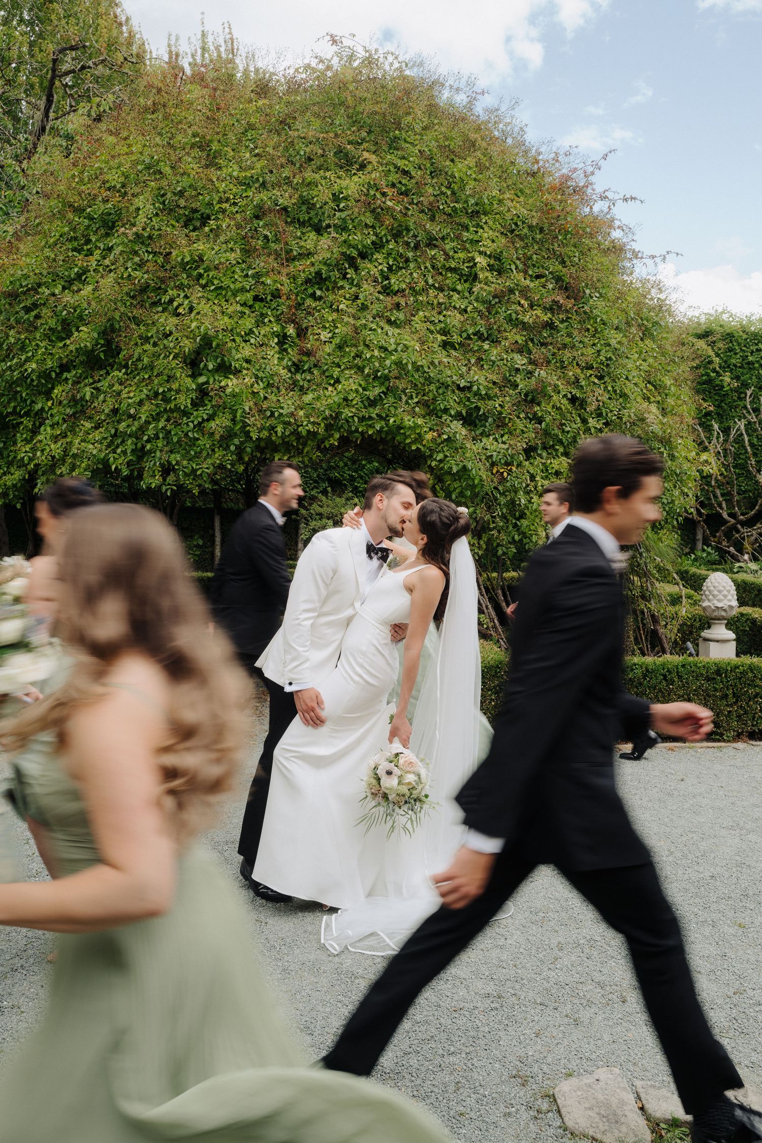 Motion-blurred sequence of wedding party dancing and celebrating outdoors.
