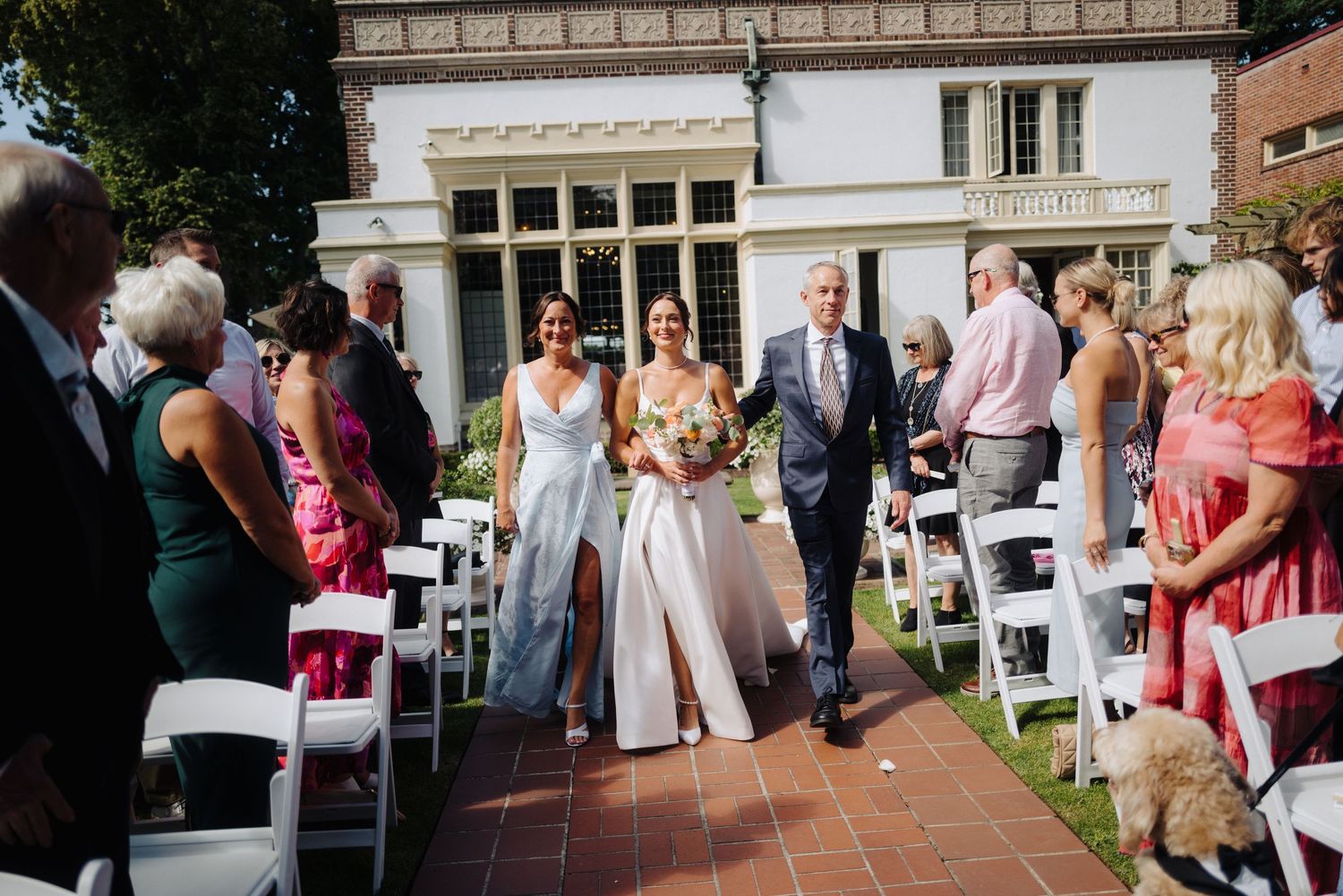 Outdoor wedding reception area with white chairs and historic building facade in background.