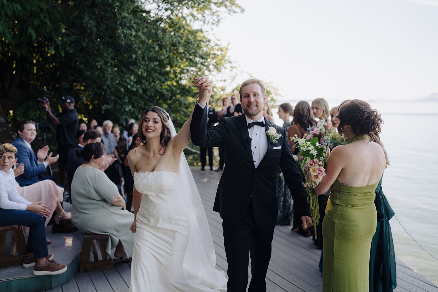 Wedding guests celebrating during an outdoor reception by the water.