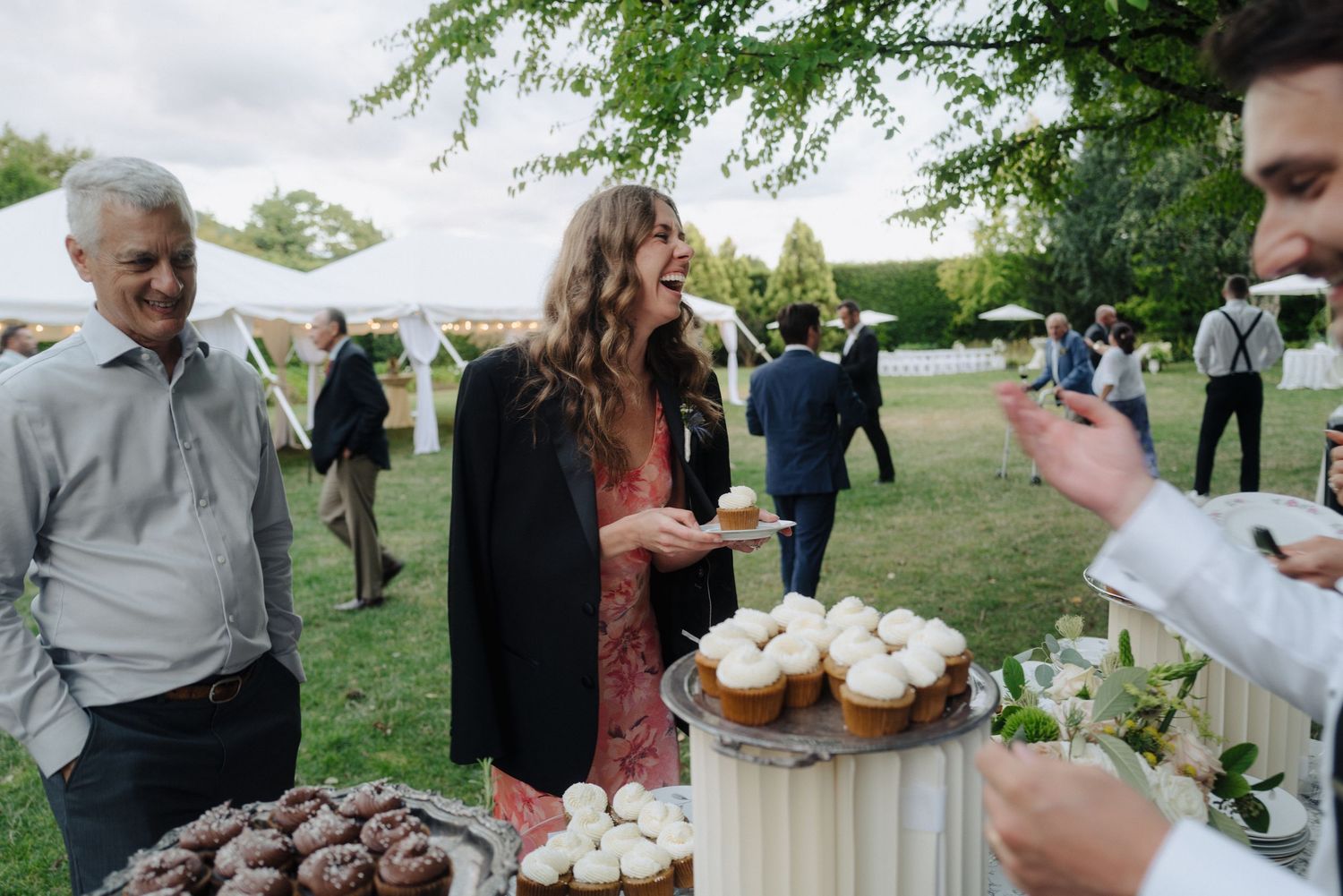 Wedding guests mingle on a lush green lawn during an outdoor reception.