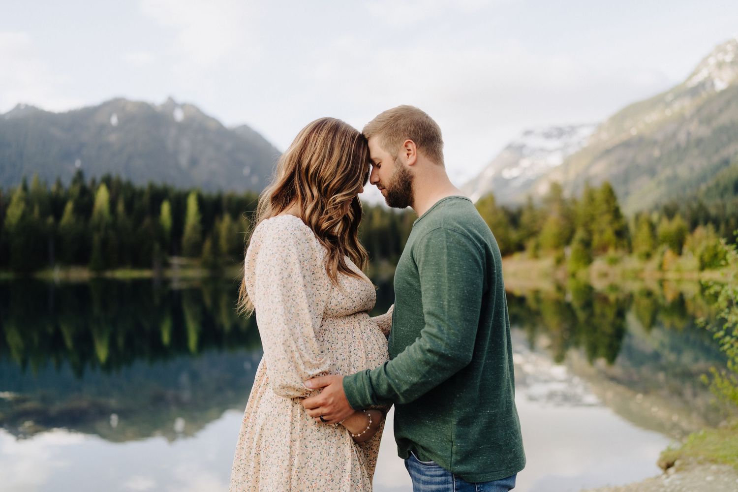 Intimate moment captured against backdrop of mountain lake and forest landscape.