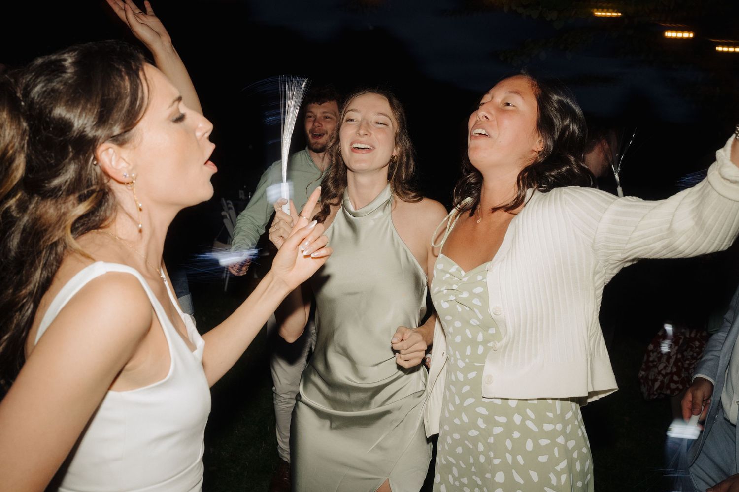 Lively nighttime wedding reception with guests dancing and celebrating.