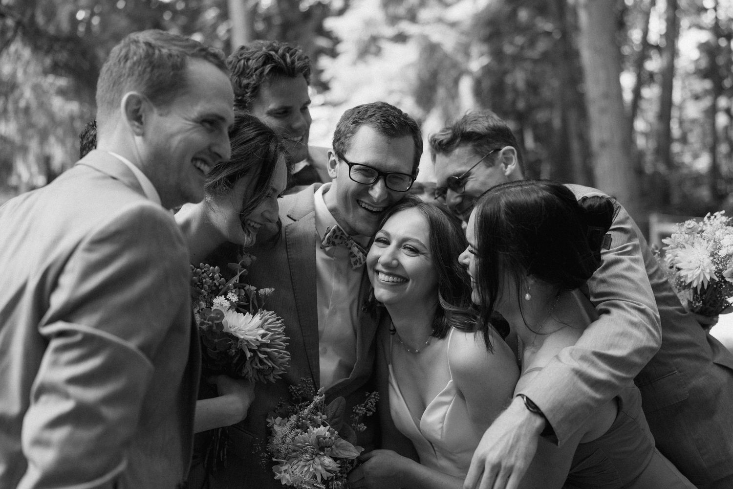 Wedding party sharing joyful moment together in black and white photography.