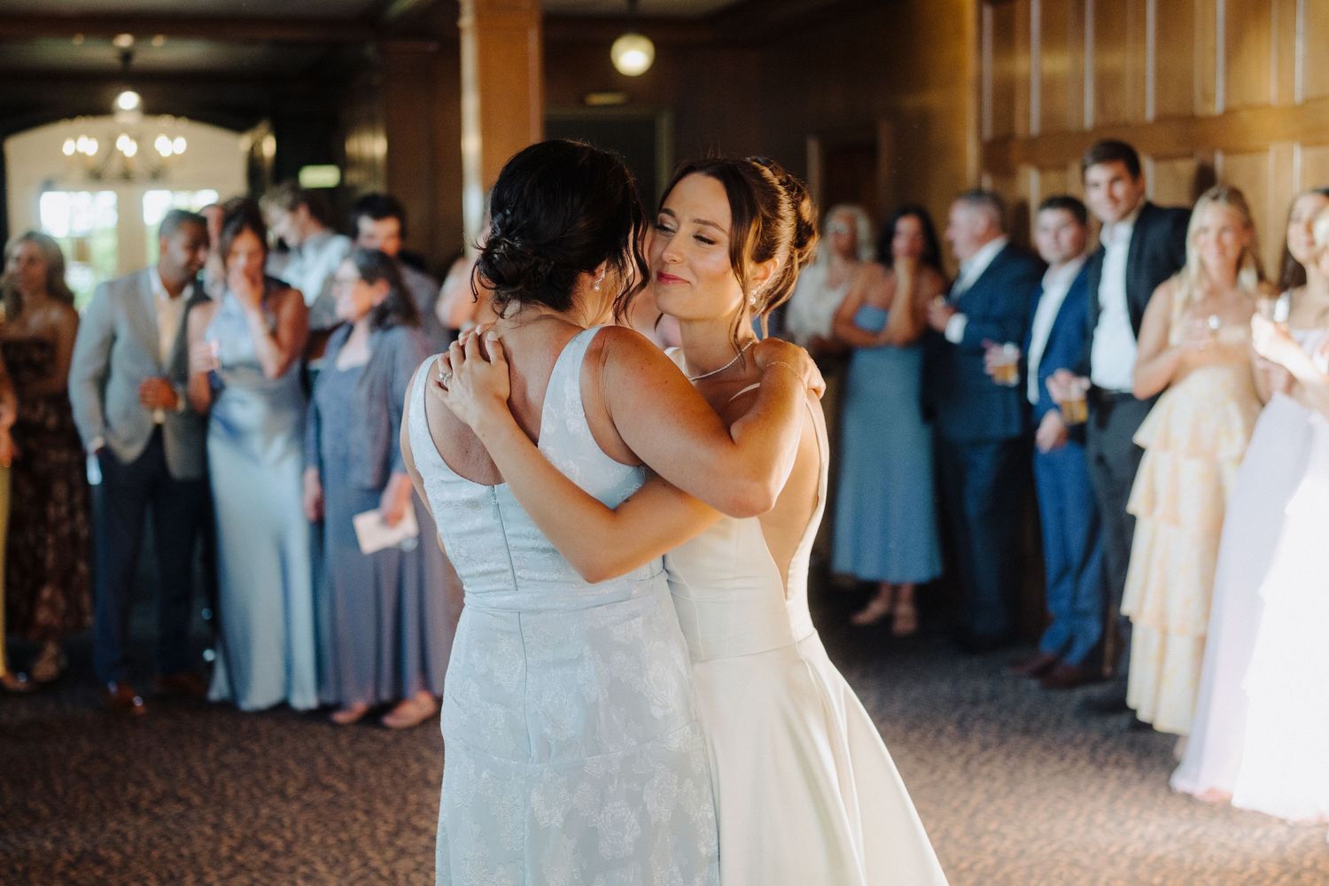 Couples dancing together during an elegant indoor wedding reception with onlooking guests.