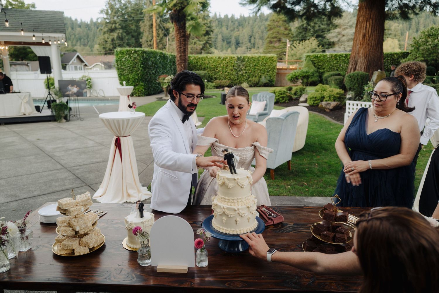 Wedding guests enjoying an outdoor reception with rustic wooden tables and natural decor.